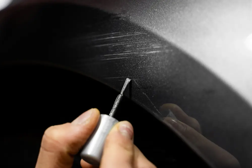 Worker using a small brush for car scratch repair in Eugene, OR