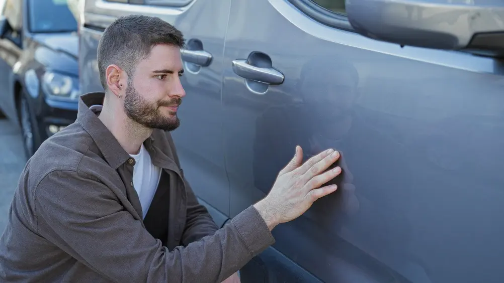 Person happily checking the finished blue car paint after auto body repair in Eugene, OR